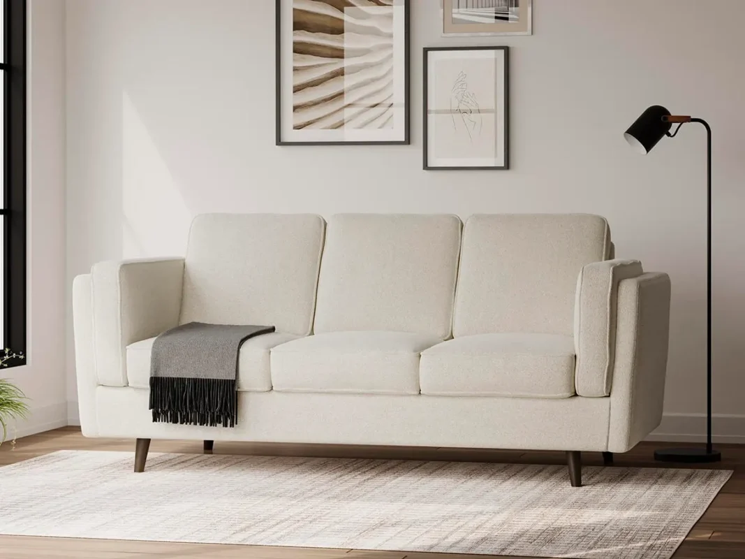 Cream fabric sofa with clean modern design in a minimalist living room with neutral decor, wall art, and soft natural lighting